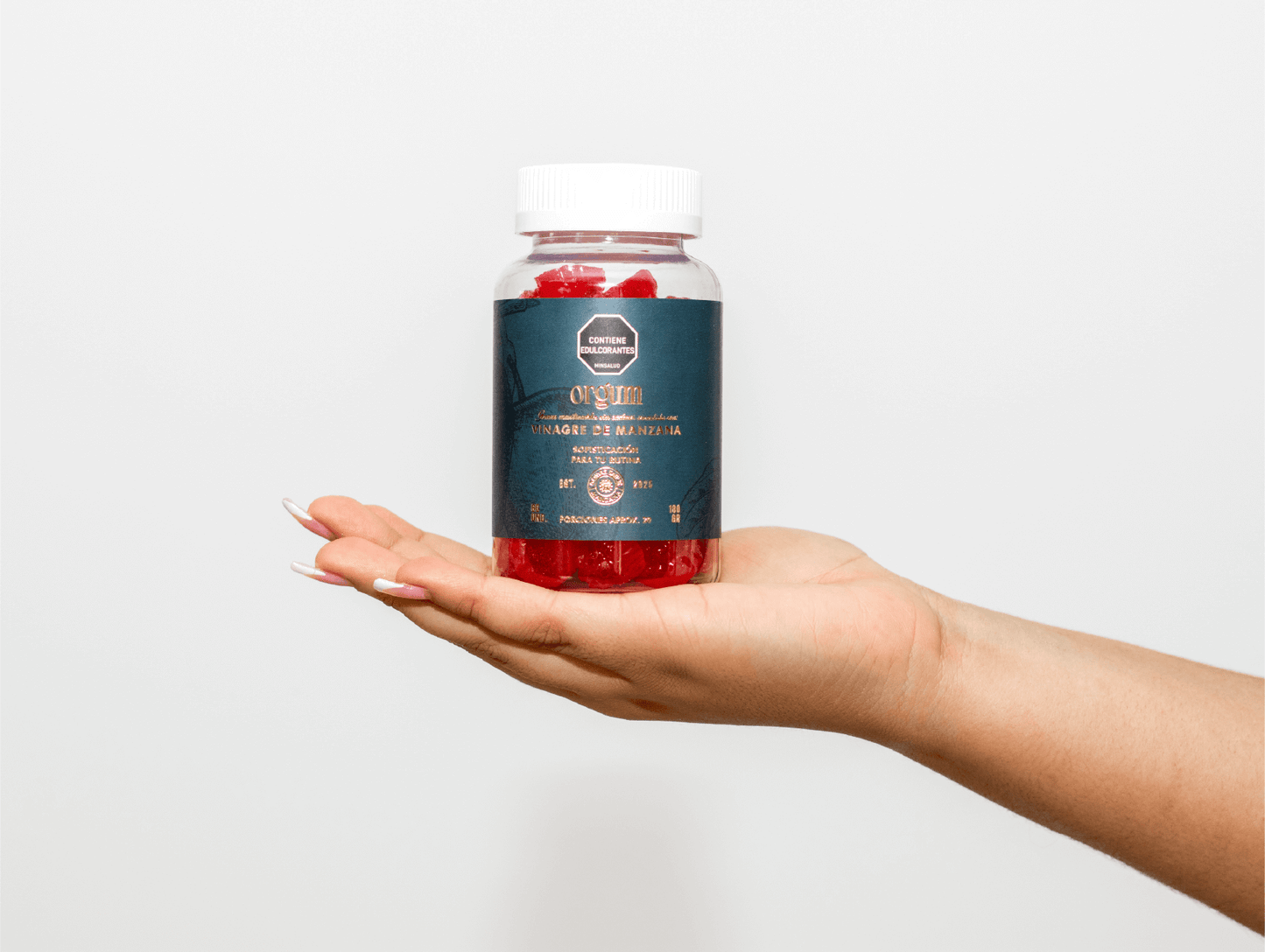 Orgum – Gomitas sin azúcar añadida con vinagre de manzana (60 unidades) presentadas en un frasco en la mano.